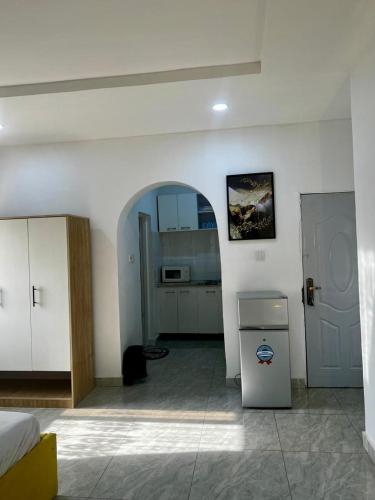 a room with a bed and a kitchen with a refrigerator at Utako Studio Apartments-City Center in Abuja