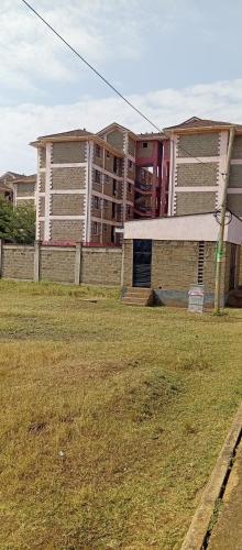 a building with a grass field in front of a building at Nolcare Cozy haven-Kisumu in Kisumu