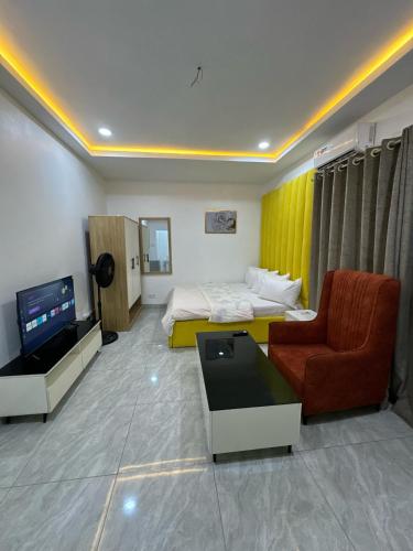 a hotel room with a bed and a couch and a tv at Utako Studio Apartments-City Center in Abuja