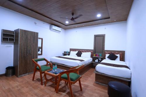 a hotel room with two beds and a table and chairs at Yashogopal Resortico in Vrindāvan