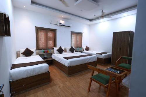 a bedroom with two beds and a table and a chair at Yashogopal Resortico in Vrindāvan