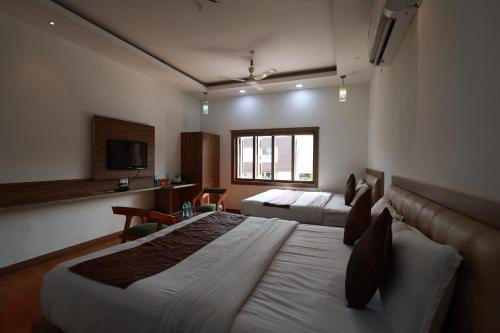 a hotel room with two beds and a television at Yashogopal Resortico in Vrindāvan