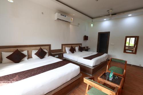 a hotel room with two beds and a table at Yashogopal Resortico in Vrindāvan