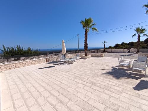 a patio with chairs and an umbrella and palm trees at Villa Nunzia in Ostuni