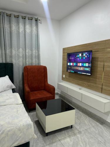 a bedroom with a bed and a tv and a chair at Utako Studio Apartments-City Center in Abuja