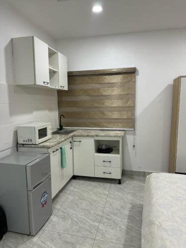 a kitchen with white appliances and a bed in a room at Utako Studio Apartments-City Center in Abuja