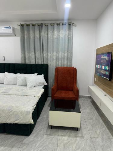 a bedroom with a bed and a chair at Utako Studio Apartments-City Center in Abuja