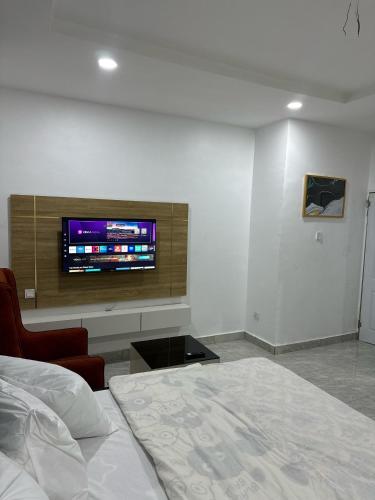 a bedroom with a bed and a tv on a wall at Utako Studio Apartments-City Center in Abuja