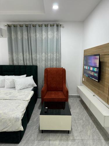 a bedroom with a bed and a chair and a tv at Utako Studio Apartments-City Center in Abuja