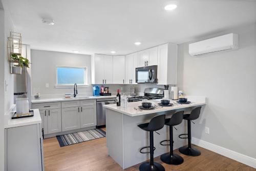 a kitchen with white cabinets and a kitchen island with bar stools at Med Center Studio Near Museums Fire Pit WiFi BBQ in Houston