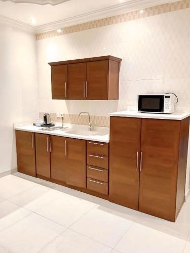 una cucina con mobili in legno e un forno a microonde di قصر القبة للشقق المخدومة Al Quba Palace - اقتصادي a Riyad