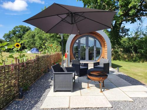 a patio with a table and chairs and an umbrella at Orielton Fach Farm - Cosy rural lodge in beautiful surroundings in Pembrokeshire