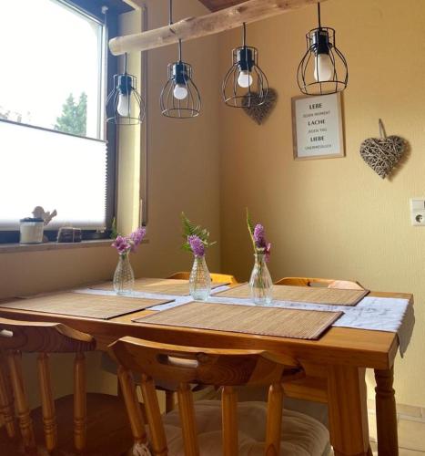 a wooden table with vases of flowers on it at Ferienwohnung Odenwaldliebe in Grasellenbach