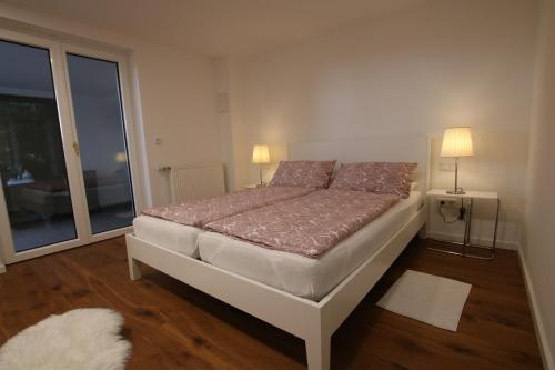 a bed in a room with two lamps and a window at Schicke Ferienwohnung für 2 in Niederkalbach