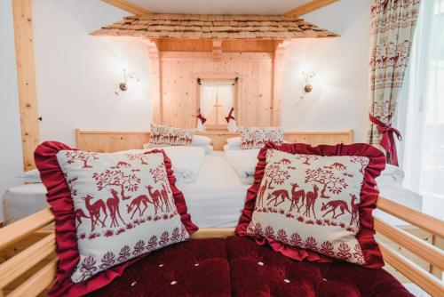 a bedroom with a bed with red and white pillows at Hotel Des Alpes in Soraga