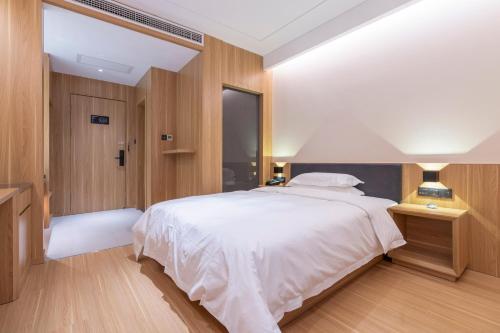 a bedroom with a large white bed and wooden walls at WeLight Hotel in Beijing