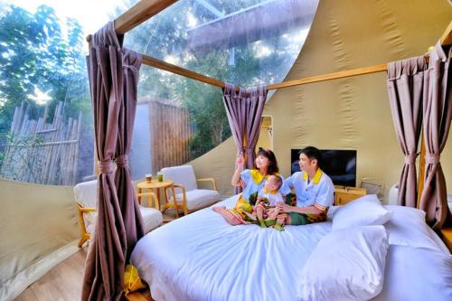 a man and woman sitting on a bed with a baby at The X10 Nordic Tent and Glamping Pool Villa Khaoyai เขาใหญ่ - SHA Certified in Ban Thung Sawang