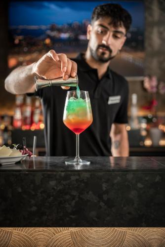 a man pouring a drink into a glass at Hotel Grazia Riccione in Riccione