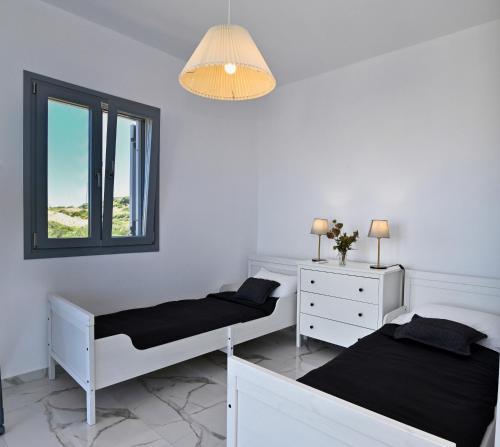 two beds in a white room with a window at Villa Almar in Adamas