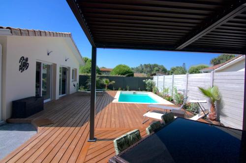 a patio with a pool and a wooden deck at Villa Coquillage in Le Teich