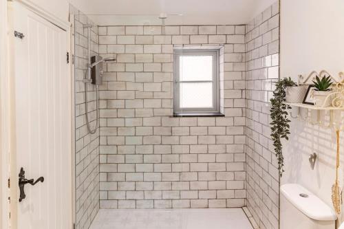 a white tiled shower with a window in a bathroom at The Lodge at Greenbank Farm 