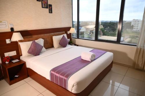 a bedroom with a large bed with a large window at Classio inn Hotel - Near Kempegowda International Airport Bangalore Terminal 1 & 2 in Bengaluru