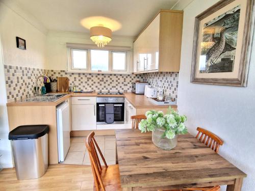 a kitchen with a wooden table with a vase of flowers on it at 93 Broadside Holiday Chalet near Broads & Beaches in Stalham