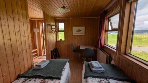 a room with two beds in a cabin with a window at Staðarhóll Guesthouse in Grenjaðarstaður