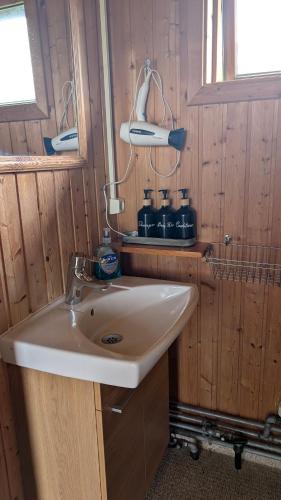 a bathroom with a sink in a wooden room at Staðarhóll Guesthouse in Grenjaðarstaður