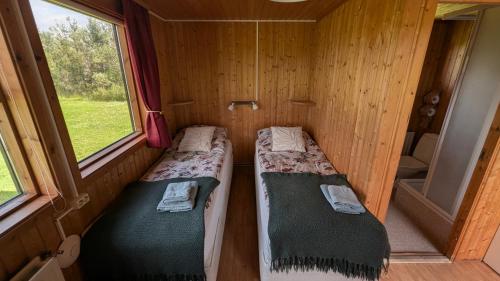 two beds in a small room with two windows at Staðarhóll Guesthouse in Grenjaðarstaður