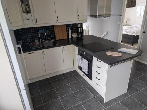 a kitchen with white cabinets and a black counter top at Cozy countryside Appartment in Örebro