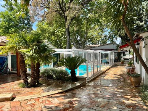une maison de verre avec des palmiers et une piscine dans l'établissement Villa de charme très grand confort à pied du centre historique d'Uzés, à Uzès