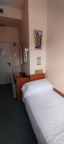 a bedroom with a large white bed and a telephone at Hotel Acerboli in Rimini