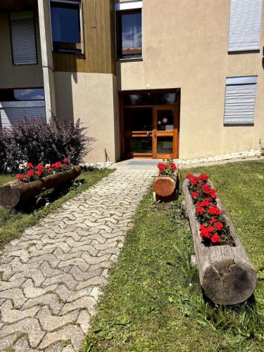 a building with a bunch of red flowers and a stone path at Studio Cosy à proximité immédiate des télécabines in Anzère