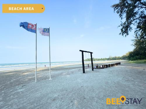 a beach with a pier and a flag on the beach at Desaru Tiara Beach Resort Pool View 3-5PAX in Bandar Penawar