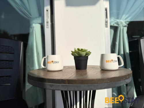 two coffee mugs on a table with a potted plant at Desaru Tiara Beach Resort Pool View 3-5PAX in Bandar Penawar