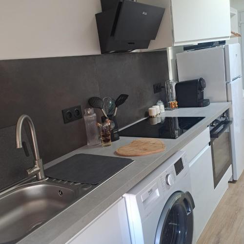 a kitchen with a sink and a washing machine at Coeur bleu de Ribérac - hyper centre in Ribérac