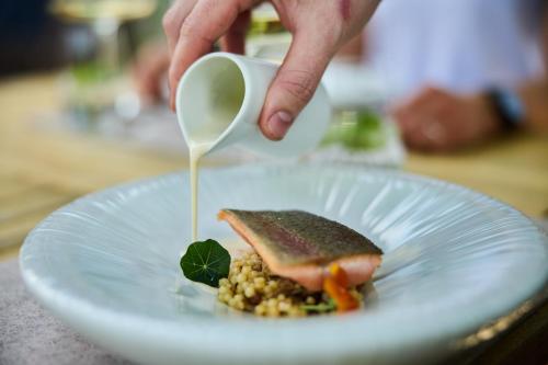 a person is pouring sauce into a sandwich on a plate at Hotel Birkenhöhe in Hirschegg