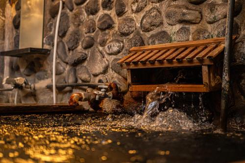 a fire hydrant in front of a stone wall at Private Onsen 泊 - Park - Tsuetate in Oguni