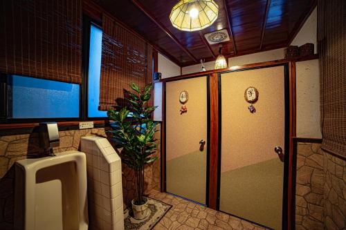 a bathroom with a urinal and a potted plant at Private Onsen 泊 - Park - Tsuetate in Oguni