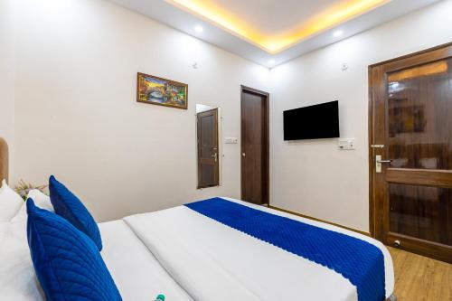 a bedroom with a bed with blue pillows and a tv at Hotel Mannat Green Near Naraina Vihar Metro Station in New Delhi