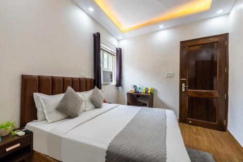 a bedroom with a large white bed and a window at Hotel Mannat Green Near Naraina Vihar Metro Station in New Delhi