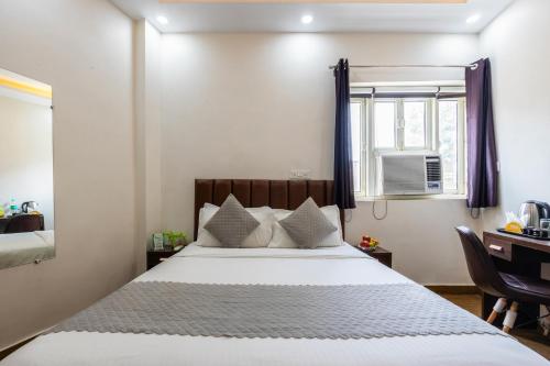 a bedroom with a bed and a desk and a window at Hotel Mannat Green Near Naraina Vihar Metro Station in New Delhi