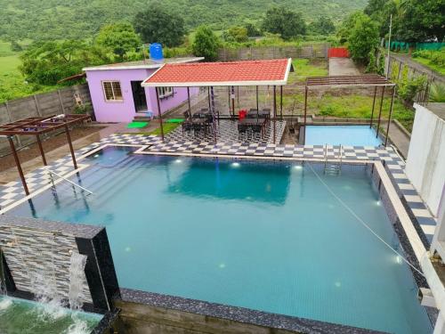 an overhead view of a large swimming pool with a house at Happy Hills Karjat in Karjat