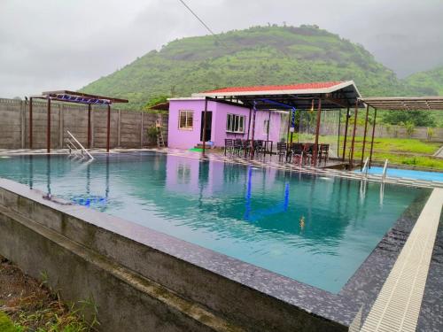 a house with a swimming pool in front of a mountain at Happy Hills Karjat in Karjat