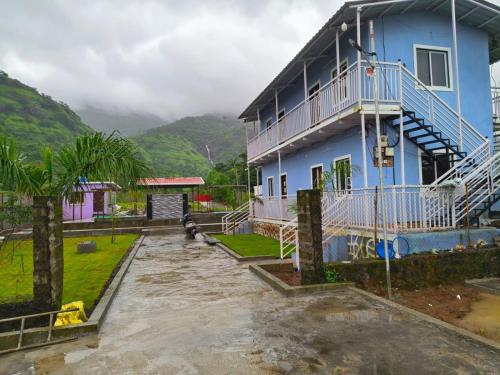 a blue house with a balcony on the side of it at Happy Hills Karjat in Karjat