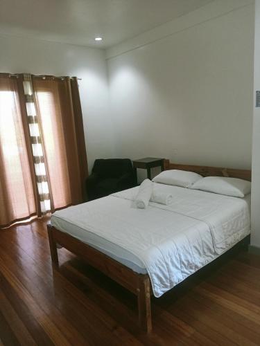 a bedroom with a bed with white sheets and pillows at Puerto Galera Hilltop Guesthouse -Tropical Retreat in Puerto Galera