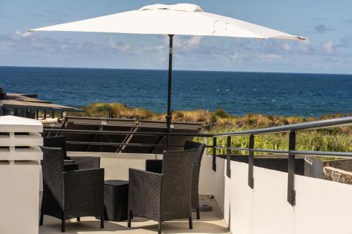 a patio with chairs and an umbrella and the ocean at Oceanside Village 4 in Lagoa