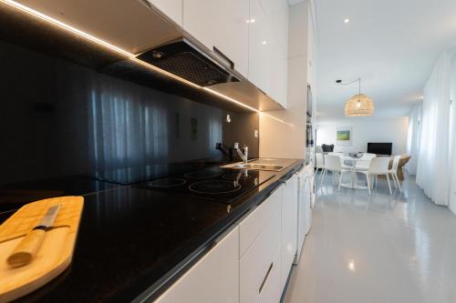 a kitchen with a black counter top and white cabinets at Oceanside Village 4 in Lagoa