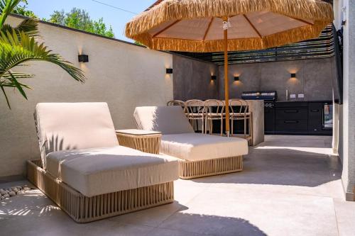 a patio with two chairs and an umbrella at אחוזת דוד - וילה יוקרתית עם בריכה פרטית in Hatzor haglilit